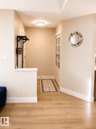 Wood-finish flooring throughout, bright recessed lighting, and a white paneled door with glass inserts - 3830 22 Street Nw, Edmonton, AB 