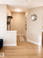 Wood-finish flooring throughout, bright recessed lighting, and a white paneled door with glass inserts - 