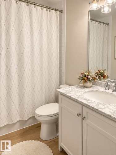 White vanity with a built-in sink, stone-finish countertop, and chrome fixtures - 3830 22 Street Nw, Edmonton, AB 