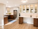 Modern kitchen featuring wood-finish flooring, two-tone cabinetry, stainless steel appliances, a built-in desk, and recessed lighting - 3830 22 Street Nw, Edmonton, AB 