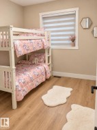 Wood-finish flooring, white trim, and a window with a roller shade - 