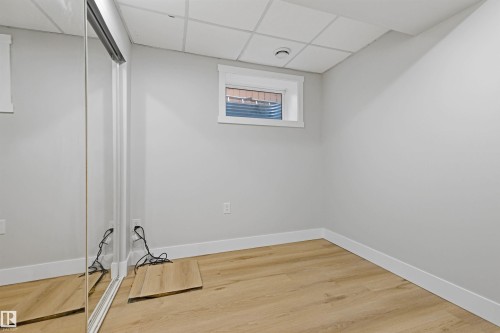 Neutral wall paint, wood-finish flooring, white trim, drop ceiling, and sliding mirrored closet doors - 3830 22 Street Nw, Edmonton, AB 