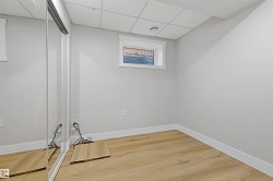 Neutral wall paint, wood-finish flooring, white trim, drop ceiling, and sliding mirrored closet doors - 