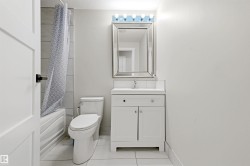 White vanity with integrated sink, chrome faucet, framed mirror, and overhead vanity lighting - 