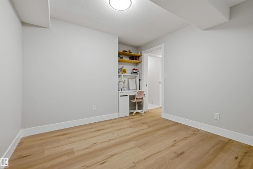 Wood-finish flooring throughout, recessed ceiling light, built-in desk with shelving, and light gray wall color - 3830 22 Street Nw, Edmonton, AB 