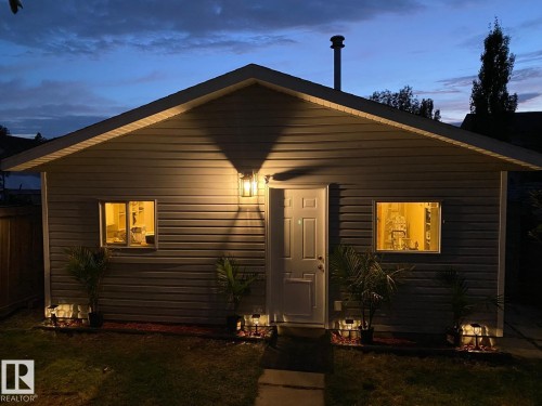 Gray horizontal siding exterior with a pitched roof, featuring a single-panel door and dual windows - 3830 22 Street Nw, Edmonton, AB 
