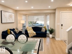 Recessed ceiling lighting, bay window, wood-finish flooring, white paneled entry door, and staircase with carpeted treads - 