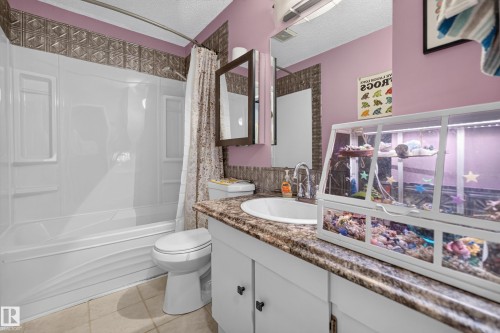 Built-in white bathtub with shower, white vanity cabinet with a brown-patterned countertop, and an integrated white sink - 333 Kirkpatrick Crescent Nw, Edmonton, AB 