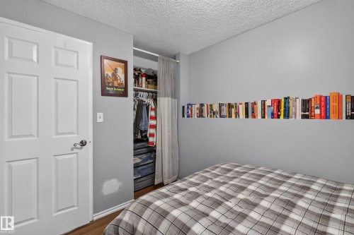 Panel door with dark hardware, built-in closet with shelving and hanging rod, and wall-mounted shelving - 333 Kirkpatrick Crescent Nw, Edmonton, AB 
