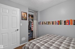 Panel door with dark hardware, built-in closet with shelving and hanging rod, and wall-mounted shelving - 