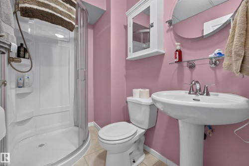 Pedestal sink with chrome fixtures, glass-enclosed shower, white wall-mounted medicine cabinet, wall-mounted mirror, and tile flooring - 333 Kirkpatrick Crescent Nw, Edmonton, AB 