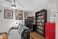 Wood-finish flooring, ceiling fan with integrated lighting, wall-mounted shelving, built-in bookshelf, and a built-in cabinet - 