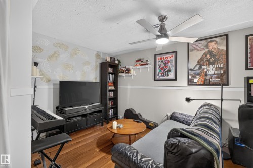 Wood-finish flooring, ceiling fan with integrated lighting, built-in shelving, decorative accent wall, and a media console - 333 Kirkpatrick Crescent Nw, Edmonton, AB 
