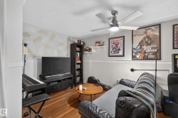 Wood-finish flooring, ceiling fan with integrated lighting, built-in shelving, decorative accent wall, and a media console - 