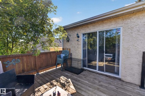 Exterior wood deck with a privacy fence, stucco siding, and a white-framed sliding glass door - 333 Kirkpatrick Crescent Nw, Edmonton, AB 