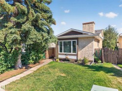 Stucco exterior with a prominent chimney, large picture window, and a gabled roofline - 