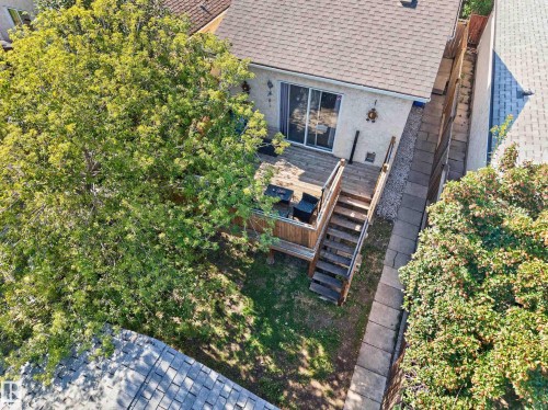 Backyard featuring a wooden deck, sliding glass door access, exterior stairs, and paved walkway - 333 Kirkpatrick Crescent Nw, Edmonton, AB 