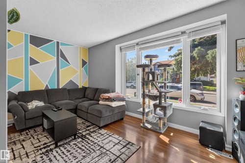 Hardwood-finish flooring, accent wall with geometric pattern, large picture windows, and ceiling-mounted light fixture - 333 Kirkpatrick Crescent Nw, Edmonton, AB 