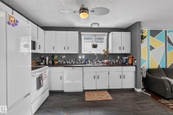 White cabinetry with black hardware, dark countertops, and a mosaic tile backsplash - 