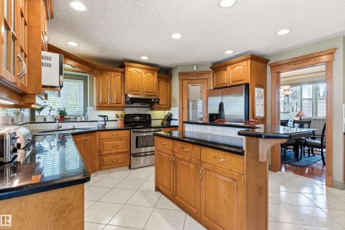 Kitchen featuring recessed lighting, extensive wood cabinetry, dark countertops, stainless steel appliances, and a central island - 703 107A Street Sw, Edmonton, AB 
