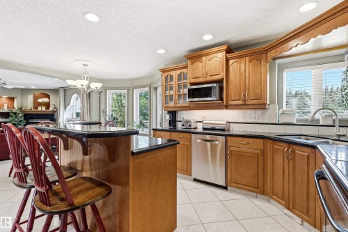 Kitchen with light wood cabinetry, dark countertops, and tile flooring - 703 107A Street Sw, Edmonton, AB 
