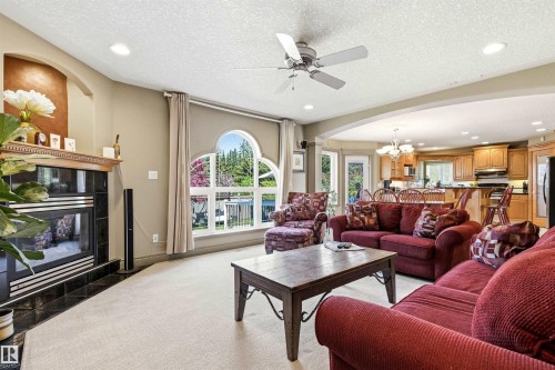Living area featuring a floor-to-ceiling fireplace with a black tile surround and wood mantel - 703 107A Street Sw, Edmonton, AB 
