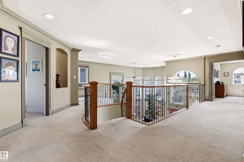 Carpeted upper level featuring a half-wall balcony with wood and wrought iron railing, arched windows, recessed lighting, and a built-in arched wall niche - 703 107A Street Sw, Edmonton, AB 