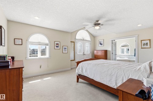 Spacious room featuring vaulted ceilings, a ceiling fan, and light-colored carpet flooring - 703 107A Street Sw, Edmonton, AB 