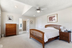 Spacious room featuring neutral carpeting, a ceiling fan with integrated lighting, and a vaulted ceiling detail - 