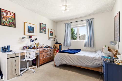 Carpeted room featuring a ceiling fan, a window with exterior views, and ample wall space - 703 107A Street Sw, Edmonton, AB 