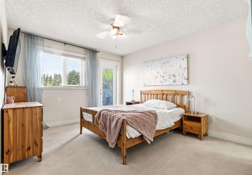 Carpeted bedroom featuring a window with horizontal blinds and a separate door providing exterior access - 703 107A Street Sw, Edmonton, AB 