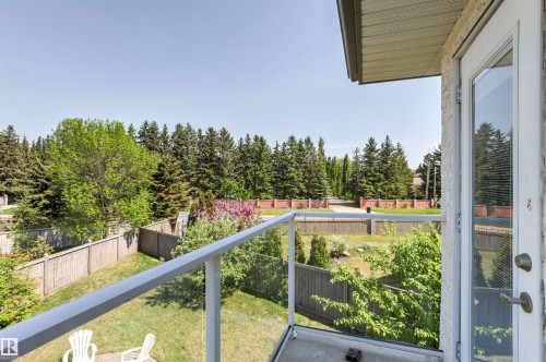 Balcony featuring glass panel railing, exterior stucco finish, and an exterior door with integrated blinds - 703 107A Street Sw, Edmonton, AB 