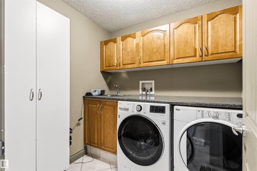 Laundry area featuring built-in cabinetry, a utility sink, and a countertop - 703 107A Street Sw, Edmonton, AB 