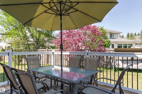 Spacious outdoor deck featuring wood-finish flooring and white railings with black spindles - 703 107A Street Sw, Edmonton, AB 