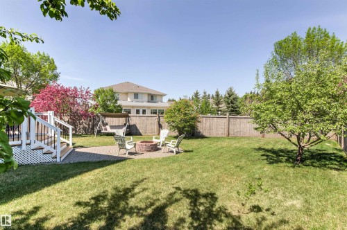 Expansive backyard featuring a lush lawn, wooden privacy fence, and mature trees - 703 107A Street Sw, Edmonton, AB 