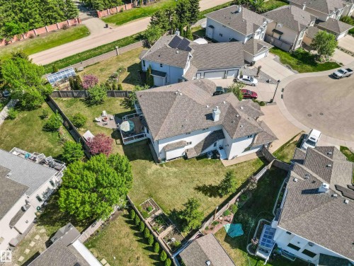 Expansive fenced backyard featuring a manicured lawn, established landscaping, a rear deck, a paved patio, and a dedicated garden area - 703 107A Street Sw, Edmonton, AB 
