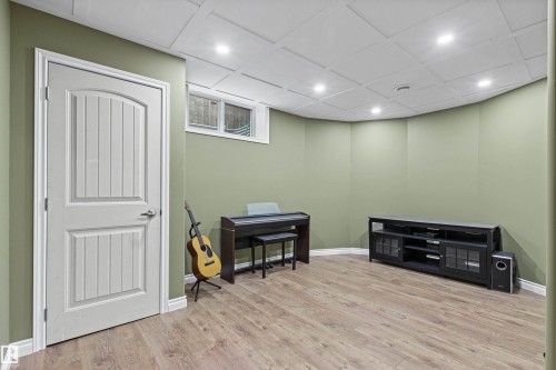 Recessed lighting, wood-finish flooring, white panel door, light green walls, and a dropped ceiling with square panels - 703 107A Street Sw, Edmonton, AB 
