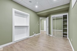 Wood-finish flooring, recessed lighting, built-in shelving, mirrored sliding closet doors, and a paneled ceiling - 