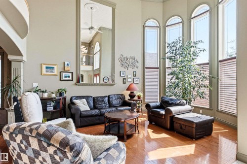 Two-story living area featuring hardwood flooring, a vaulted ceiling, and multiple arched windows - 703 107A Street Sw, Edmonton, AB 