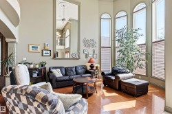 Two-story living area featuring hardwood flooring, a vaulted ceiling, and multiple arched windows - 