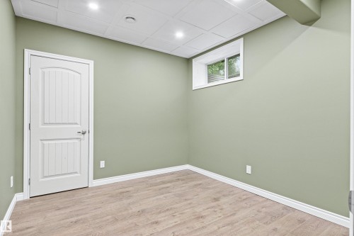 Recessed lighting, wood-finish flooring, white paneled door, window with white trim, and a white ceiling with a textured finish - 703 107A Street Sw, Edmonton, AB 