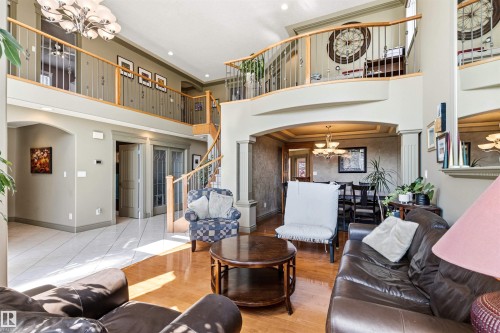 Two-story living area featuring a spiral staircase, open-concept design, wood-finish flooring, tiled entry, and an upper-level overlook with an ornate railing - 703 107A Street Sw, Edmonton, AB 