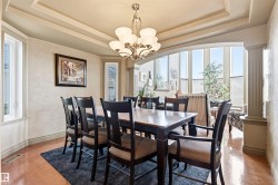 Dining area featuring a tray ceiling with crown molding, a brass chandelier, and wood-finish flooring - 