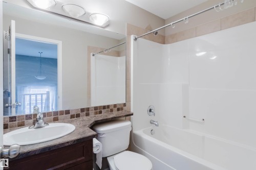 Tub/shower combination with chrome fixtures, vanity with integrated sink, patterned tile backsplash, and overhead lighting - 11608 96 Street Nw, Edmonton, AB 
