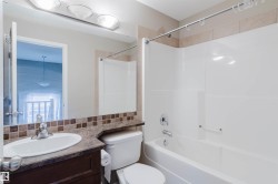 Tub/shower combination with chrome fixtures, vanity with integrated sink, patterned tile backsplash, and overhead lighting - 
