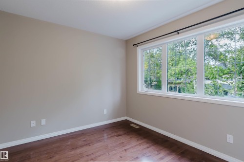 Wood-finish flooring, neutral wall tones, large window with multiple panes, ceiling-mounted lighting fixture - 11608 96 Street Nw, Edmonton, AB 