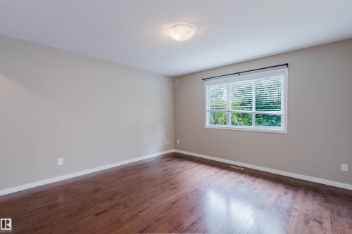 Hardwood-finish flooring, neutral wall paint, and a large window with white blinds - 11608 96 Street Nw, Edmonton, AB 
