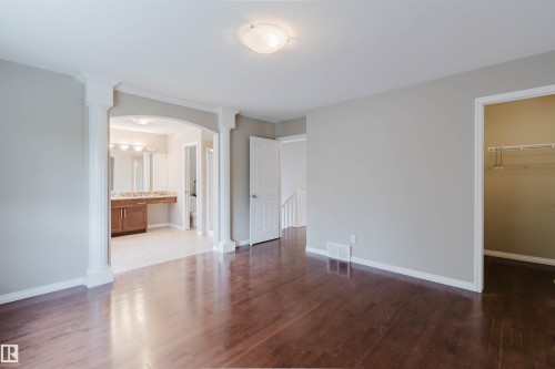 Hardwood-finish flooring, architectural archway with decorative columns, recessed lighting, double vanity with integrated sinks, and tiled bathroom flooring - 11608 96 Street Nw, Edmonton, AB 