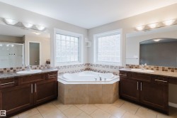 Dual vanity sinks, corner soaking tub, tile flooring, glass block windows, and a tiled shower enclosure - 