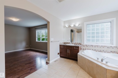 Bathroom with a built-in jetted tub, tile surround, and a vanity with an integrated sink - 11608 96 Street Nw, Edmonton, AB 